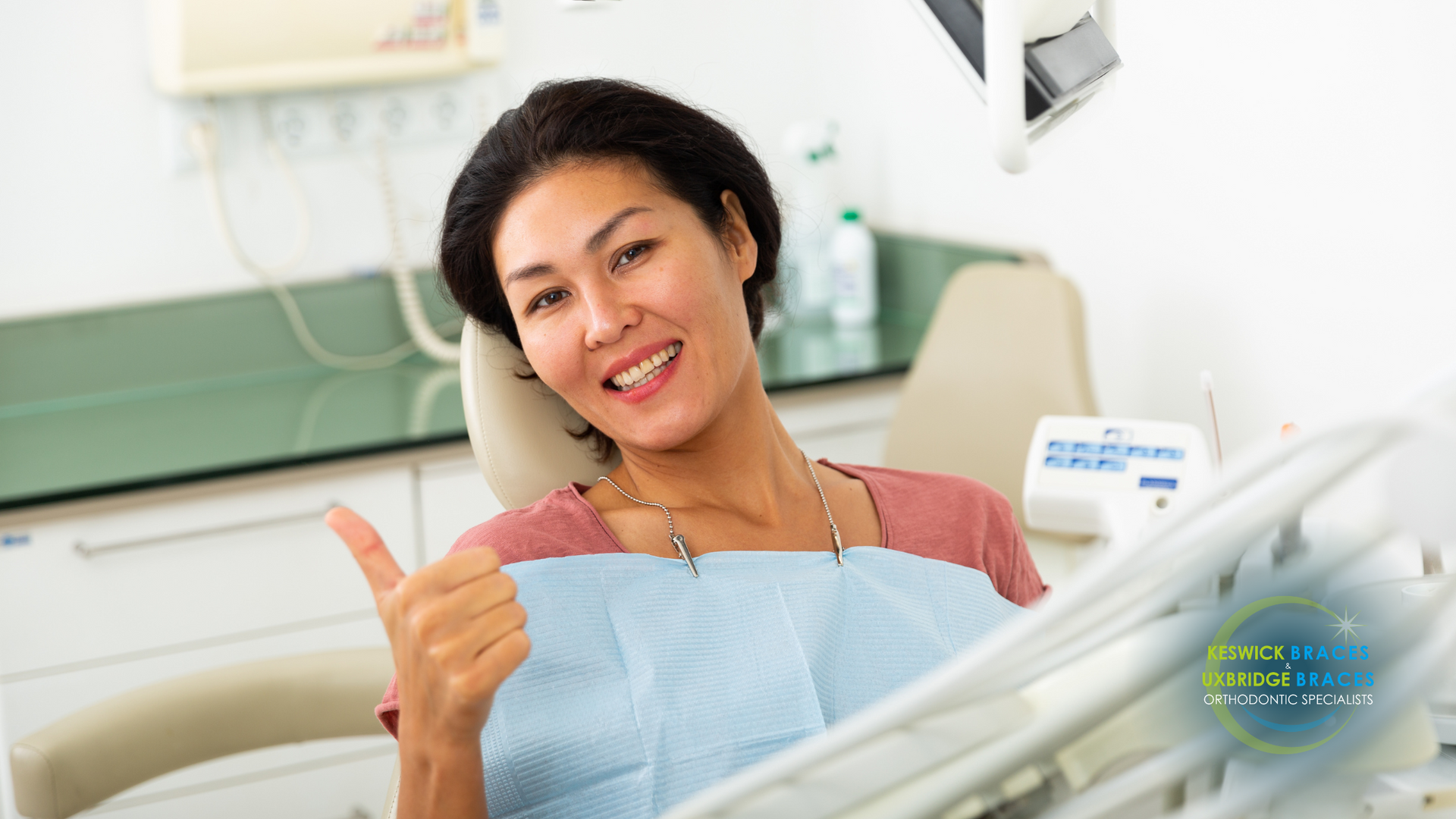 A woman is giving a thumbs up while sitting in a dental chair.
