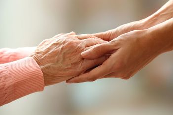 Two hands gently holding in a close-up against a soft blurred background
