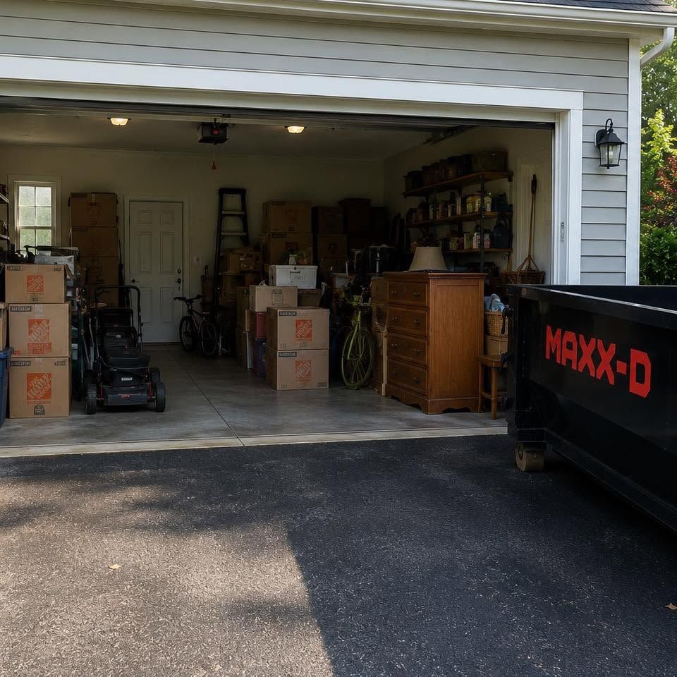Garage filled with moving boxes and equipment, with a black Maxx-D trailer parked outside.