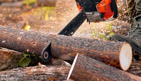 A person is cutting a log with a chainsaw.