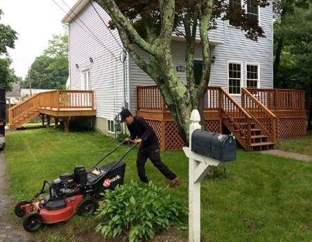A man is mowing the lawn in front of a house