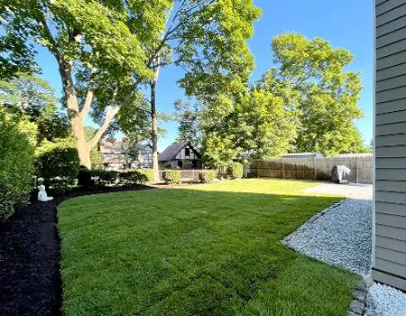 A large lush green yard with a house in the background.