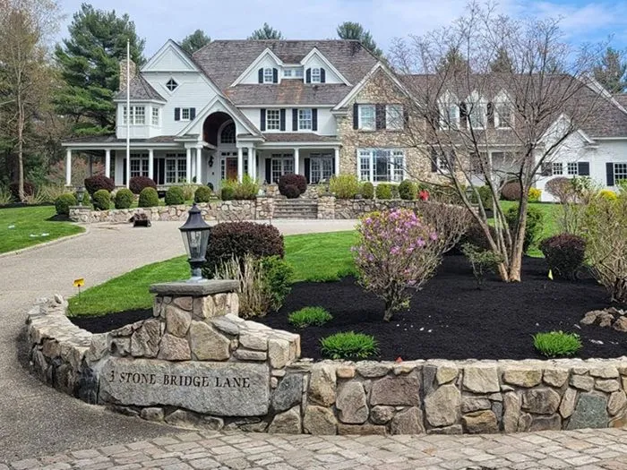 Large two-story house with stone accents, circular driveway, and well-maintained landscaping.
