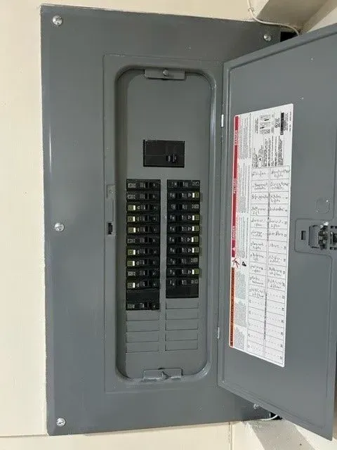 A gray electrical box with the door open on a wall.