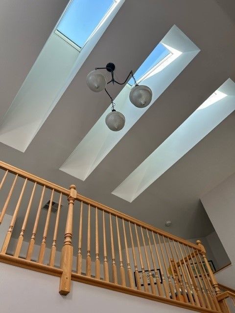 A staircase with a wooden railing and skylights on the ceiling