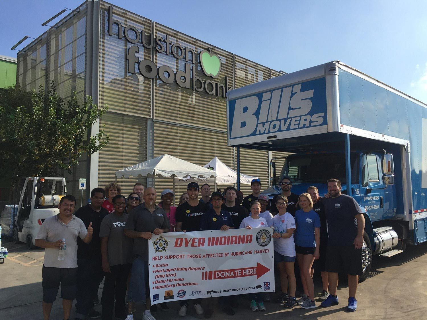 Group posing with a banner in front of a Blue Bonnet Foods truck at an outdoor event