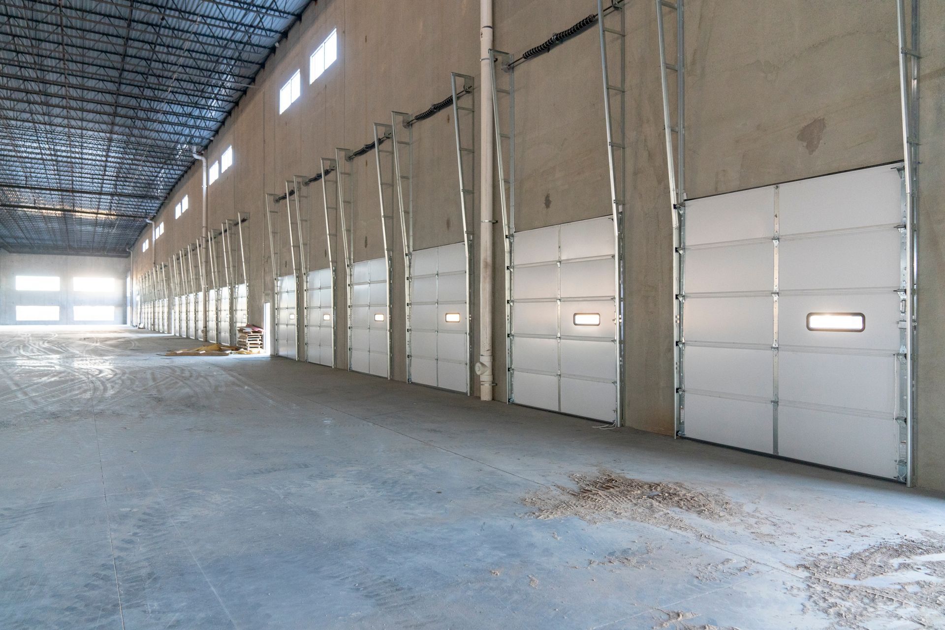 Empty industrial warehouse interior with large white doors and a high metal ceiling