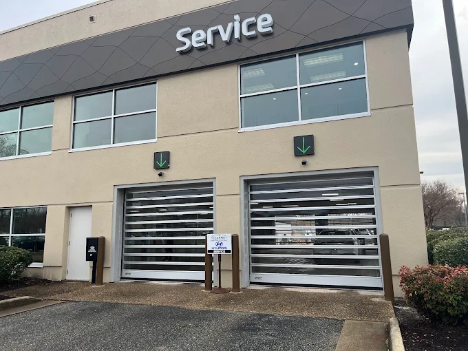 Service building with two garage bays, beige facade, and dark awning over the entrance