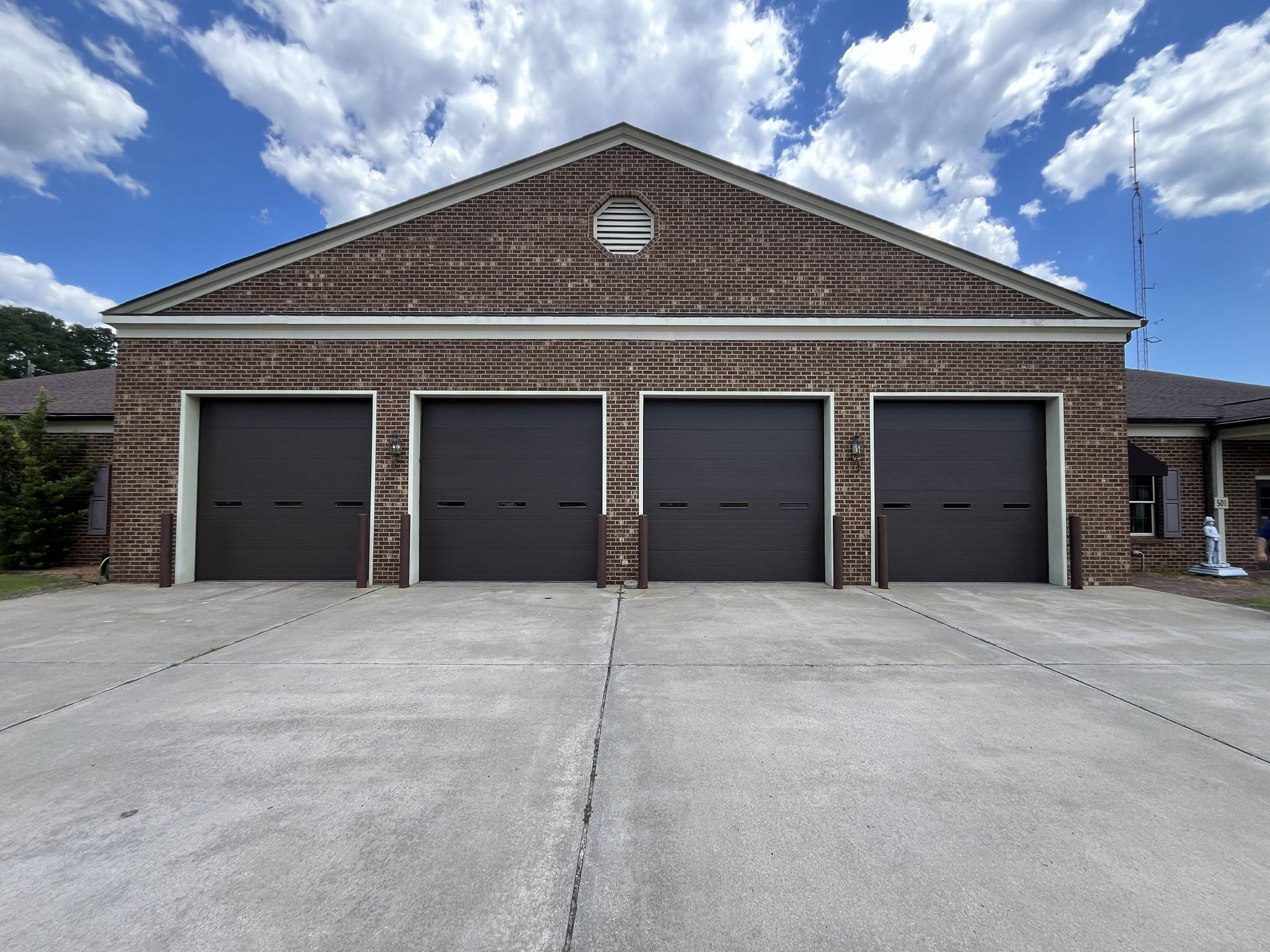 Brick garage building with four dark doors under a blue sky