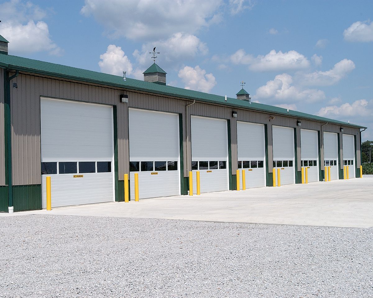 Modern industrial building with two large blue garage doors under a bright blue sky