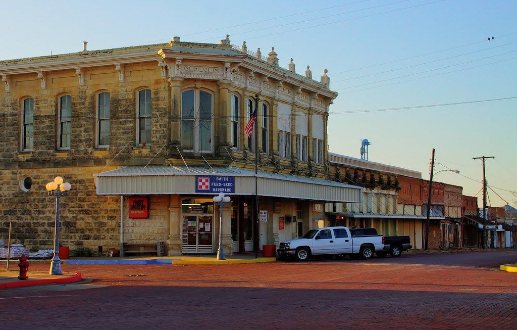 A white truck is parked in front of a large building.