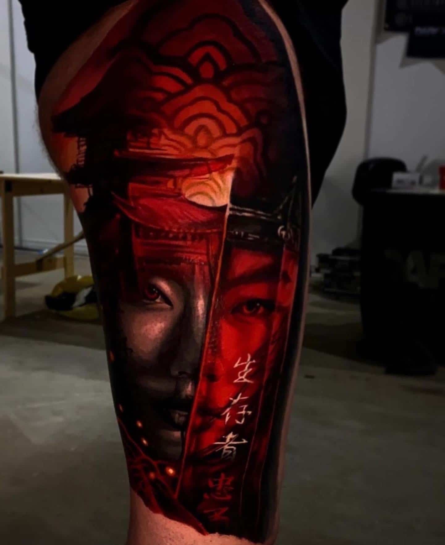 A vibrant, detailed tattoo featuring a split face design in red and black, adorned with traditional Asian-style motifs.