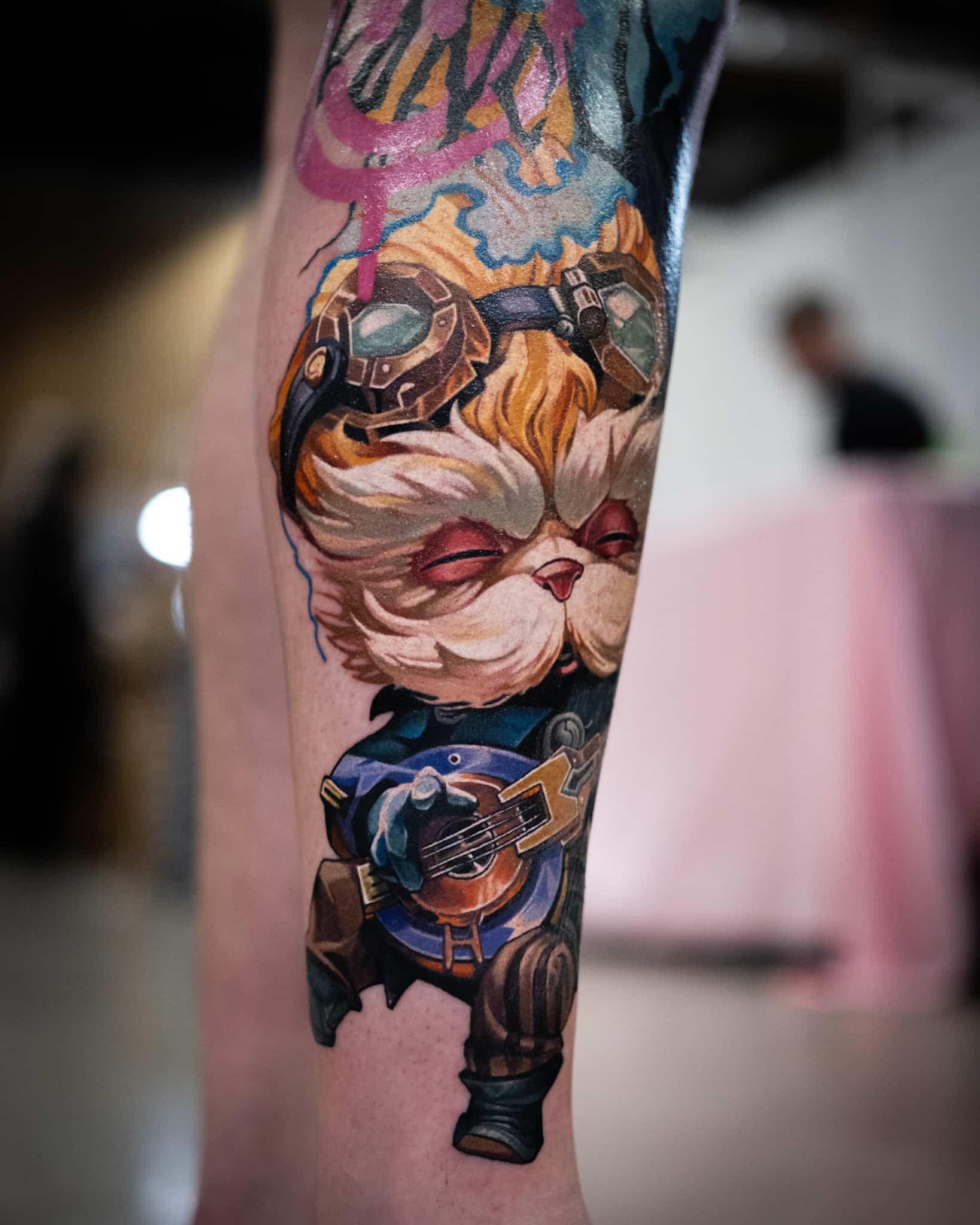 A vibrant tattoo of Heimerdinger from League of Legends playing a lute, on a person’s lower leg.