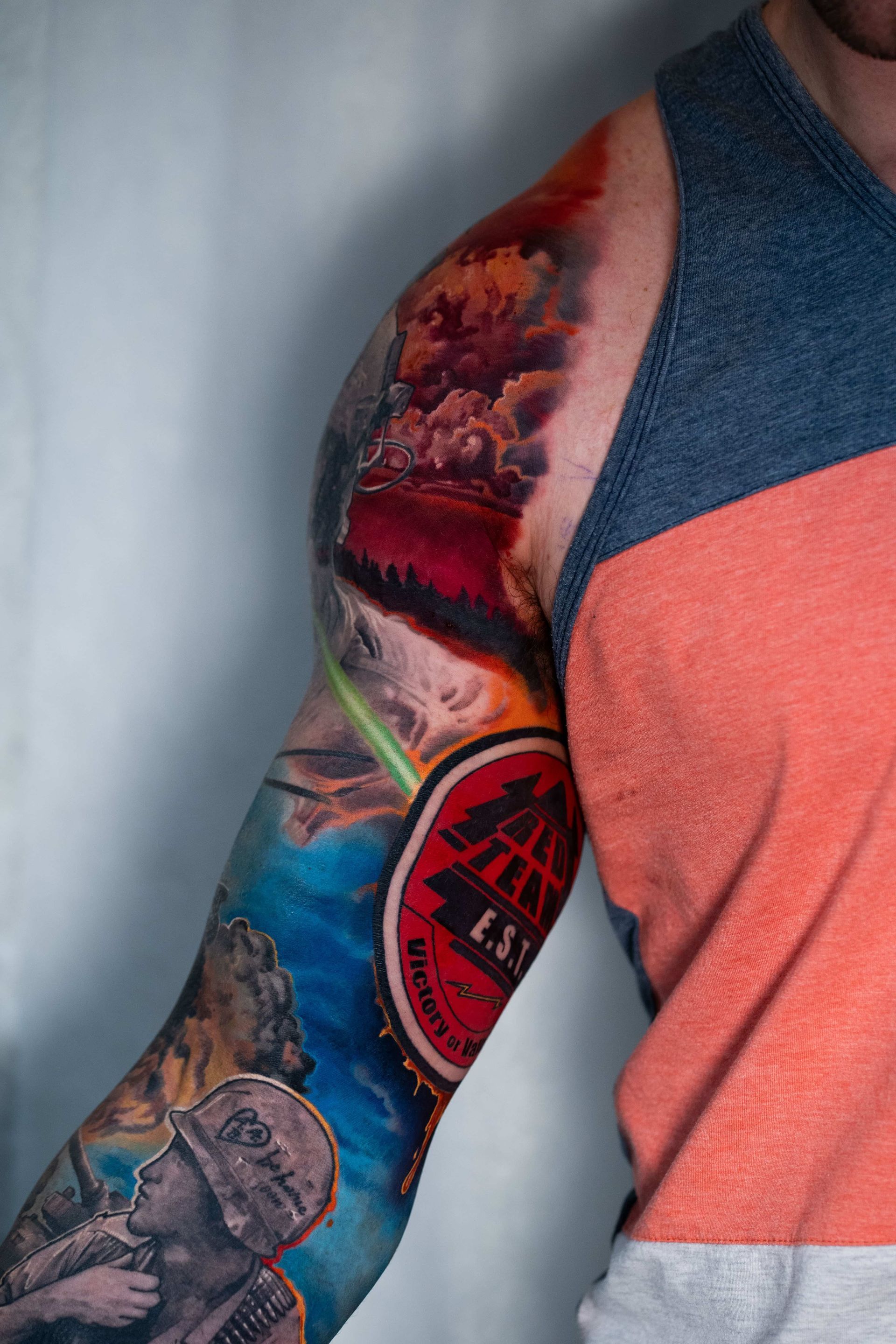 A person's arm with a colorful military-themed sleeve tattoo, including a soldier in a helmet and red imagery.