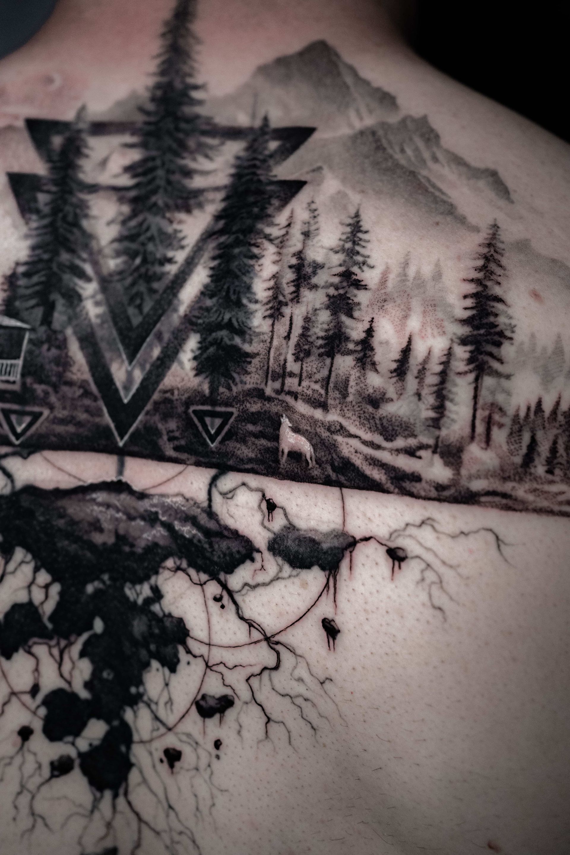 Back tattoo featuring a landscape of pine trees and mountains integrated with geometric shapes and stylized tree roots.