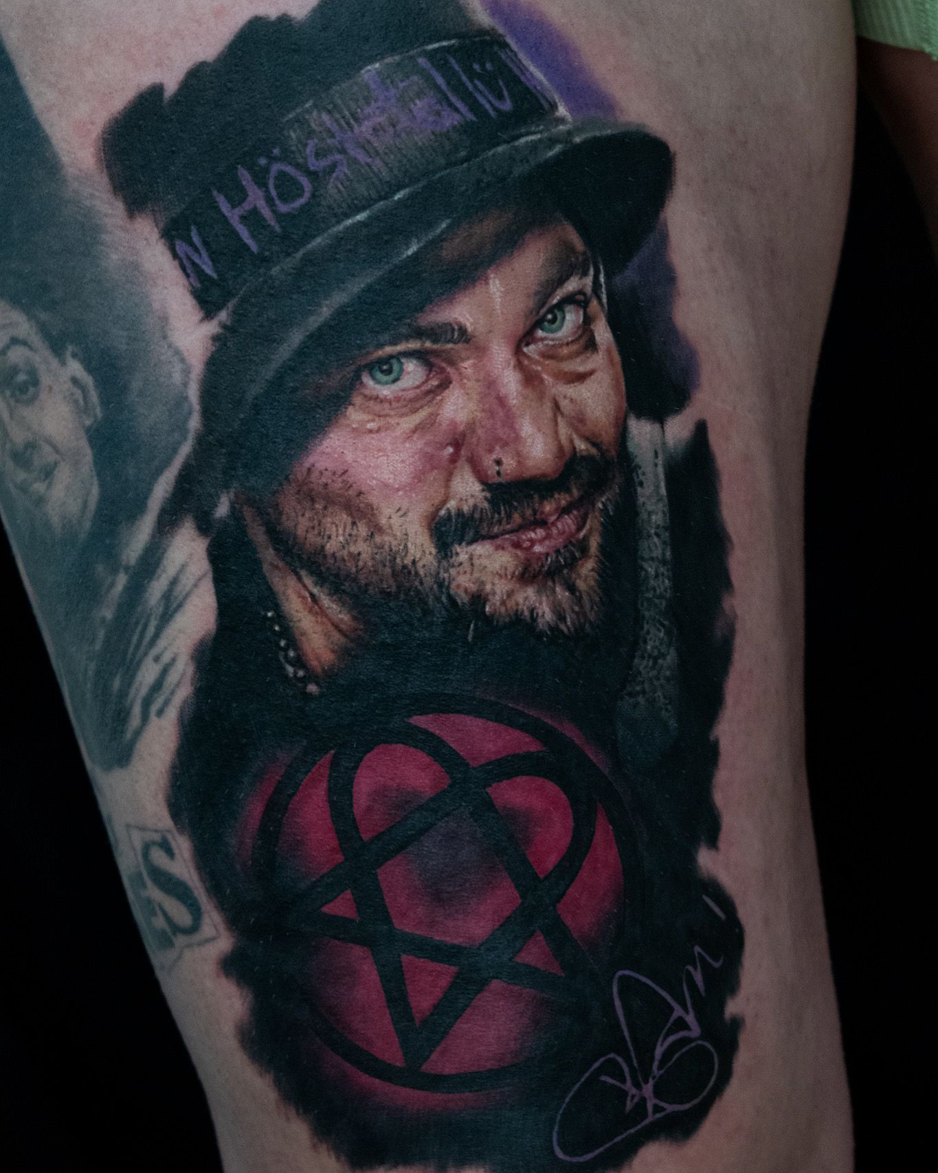 A detailed tattoo of a man wearing a hat with the word