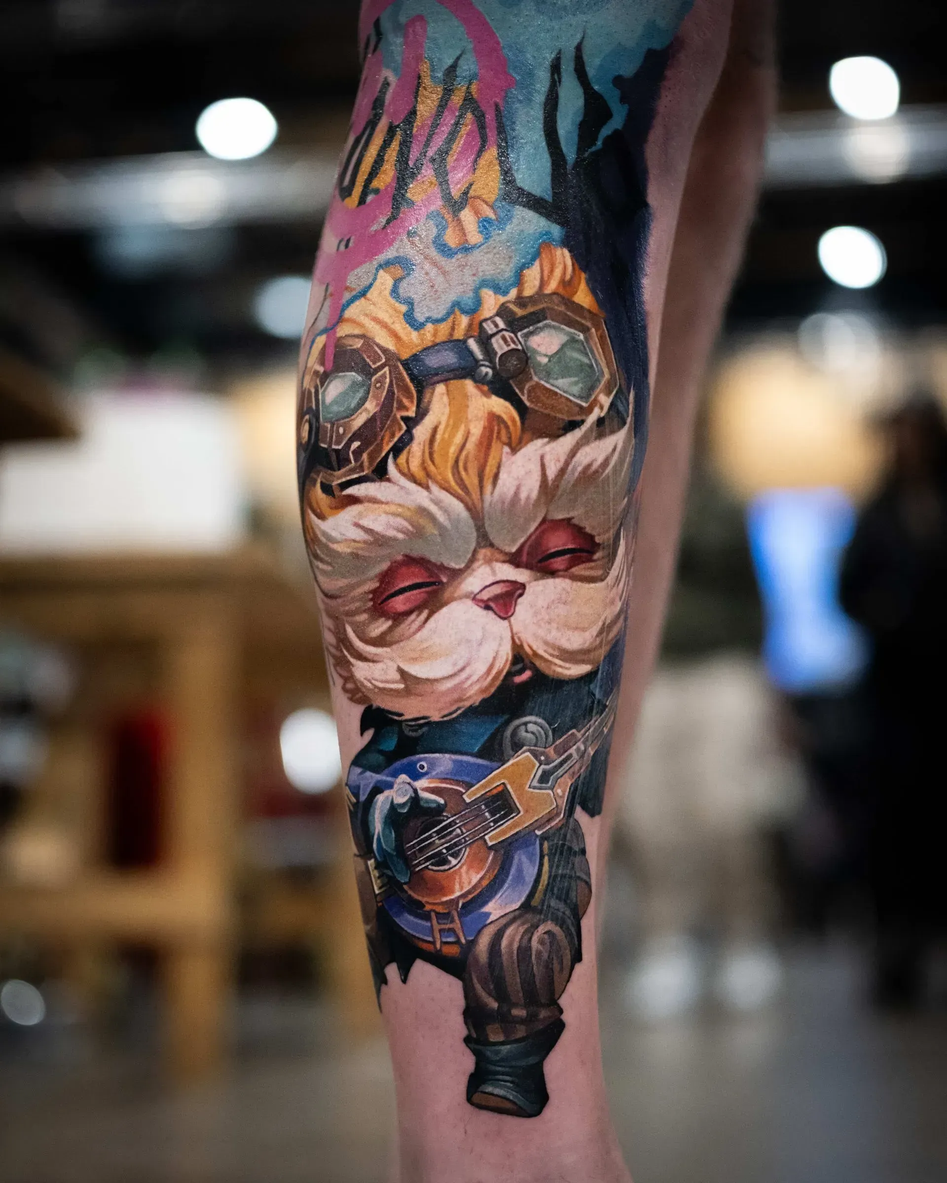 A colorful tattoo on a person's calf featuring Heimerdinger from League of Legends playing a guitar with goggles on.