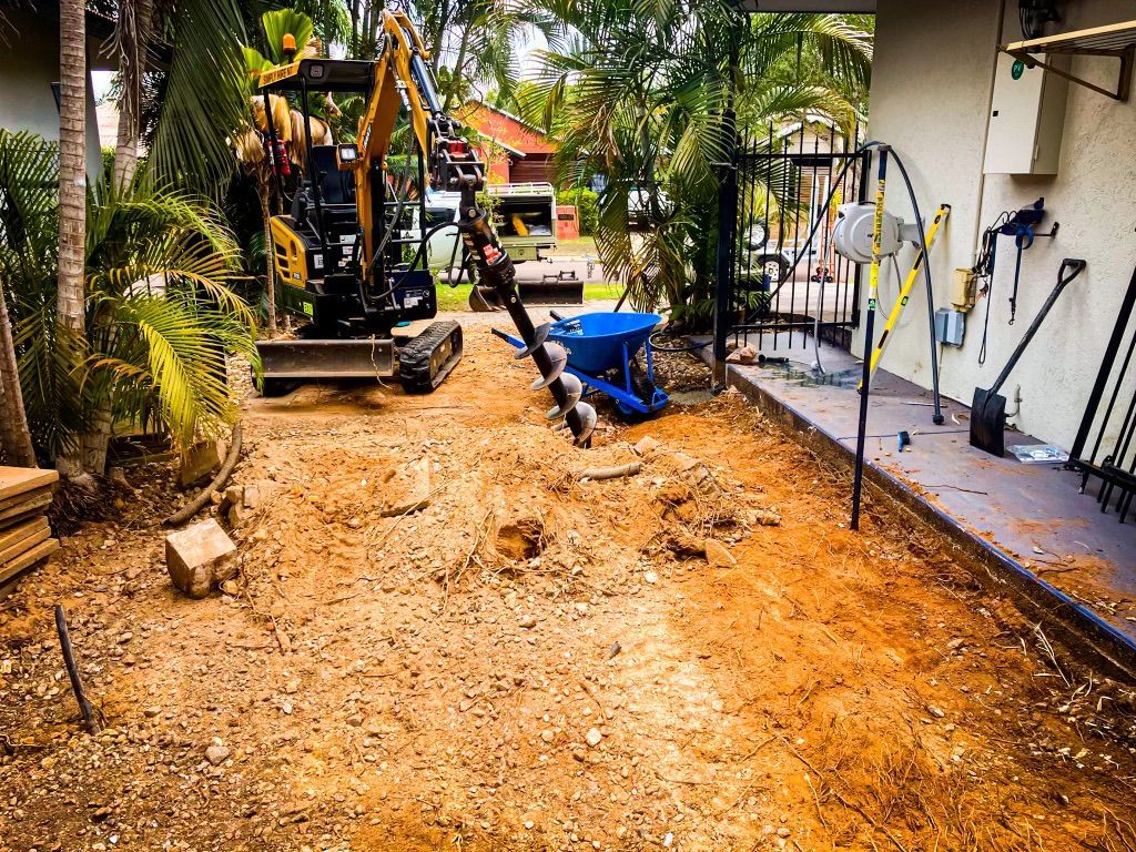 A Small Excavator is Working on a Dirt Road in Front of a House — Fewmore Contracting in Yarrawonga, NT