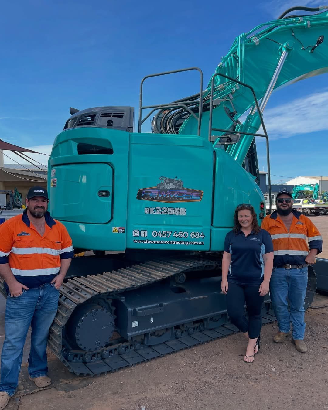 A group of people are standing in front of a large excavator.