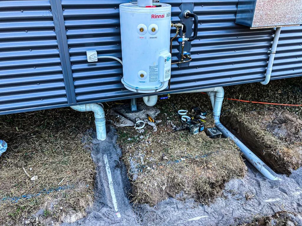 A Water Heater is Attached to the Side of a Building — Fewmore Contracting in Yarrawonga, NT