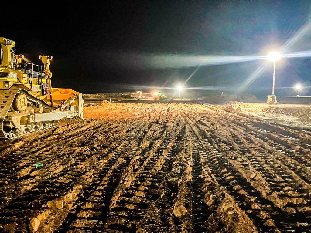 A Bulldozer is Working on a Dirt Field at Night — Fewmore Contracting In Tennant Creek, NT