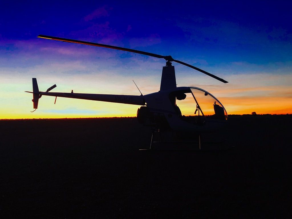 A Helicopter is Silhouetted Against a Sunset Sky — Fewmore Contracting In Tennant Creek, NT