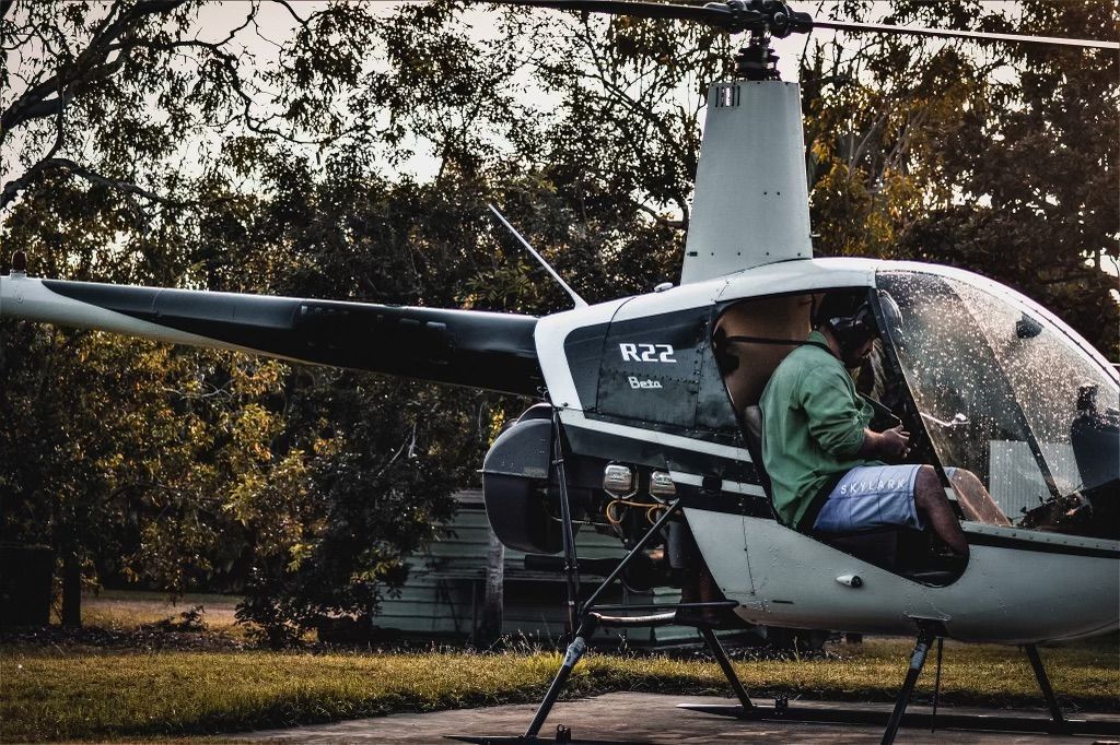A Man is Sitting in the Cockpit of a Small Helicopter — Fewmore Contracting in Yarrawonga, NT