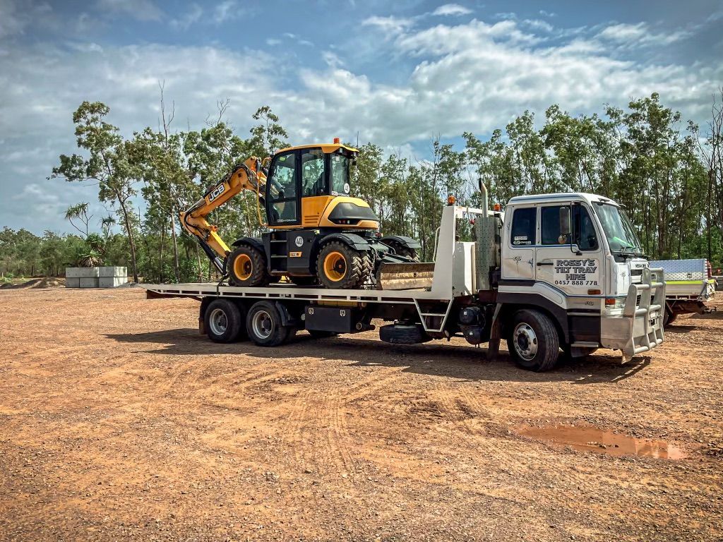 A Truck is Carrying a Yellow Excavator on the Back of It — Fewmore Contracting in Yarrawonga, NT