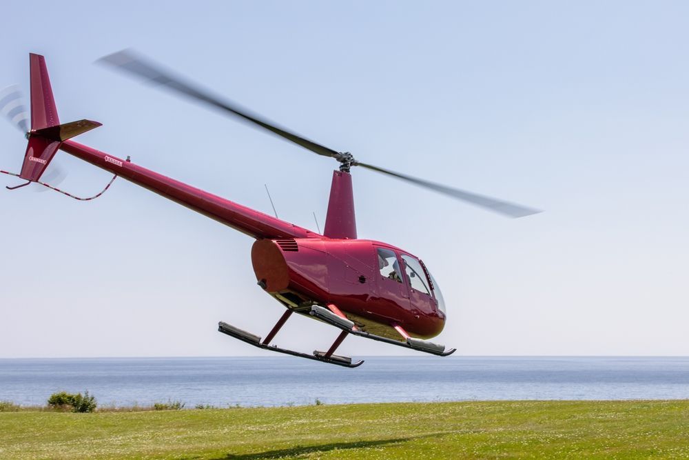 A Red Helicopter is Flying Over a Grassy Field Near the Ocean — Fewmore Contracting in Humpty Doo, NT