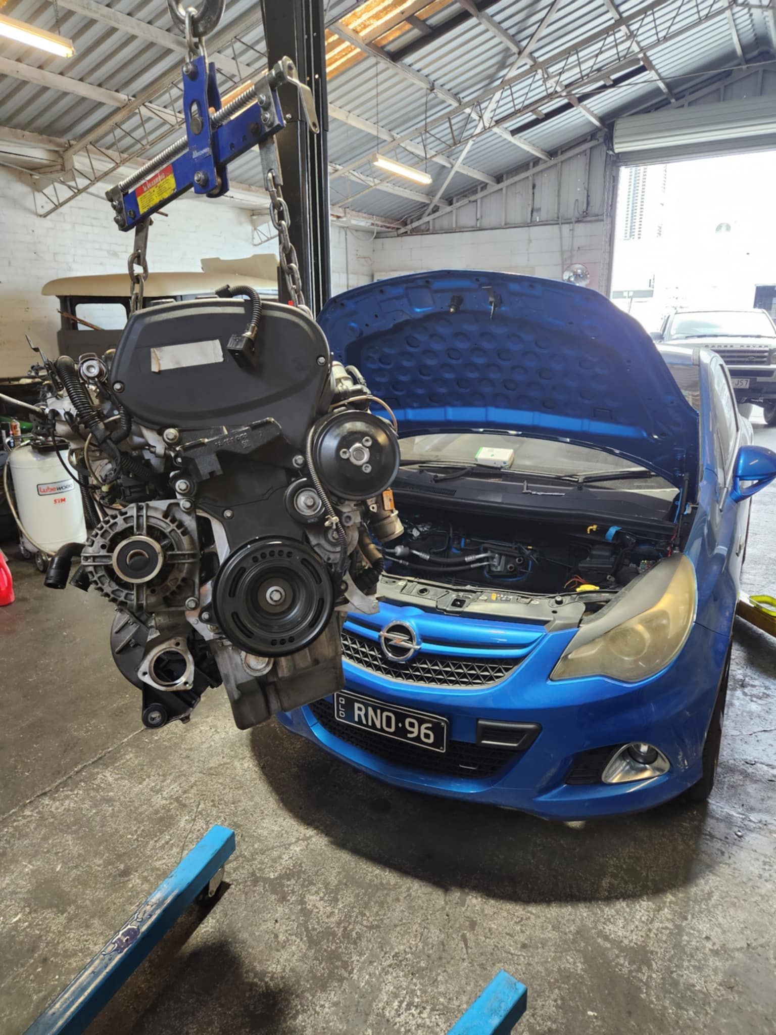 Engine on a Lift In Front of Blue Car β Sebring All Mechanical Repairs In Mermaid Beach, QLD