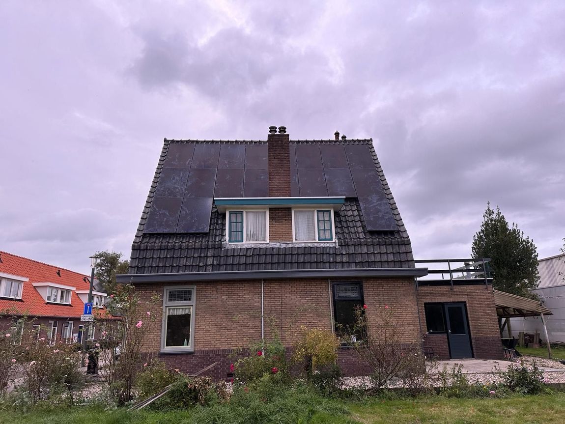 Een groot bakstenen huis met zonnepanelen op het dak.