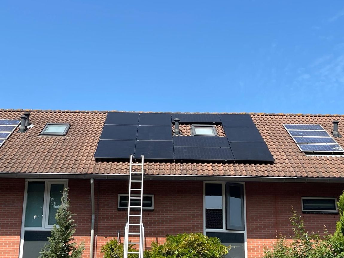 Er staat een ladder op het dak van een huis met zonnepanelen erop.