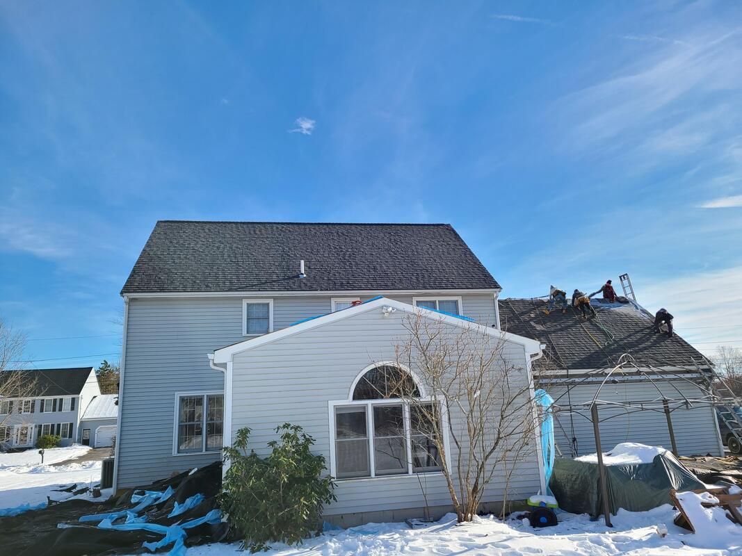 Two-story house with light blue siding, snow on the ground, and a clear blue sky.