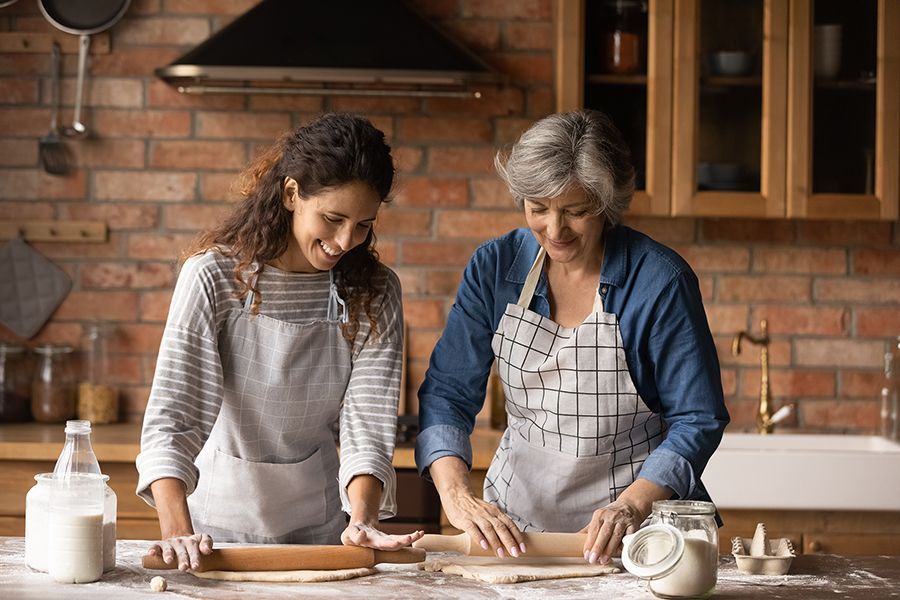 Family Elder Mother and Adult Daughter cooking in kitchen