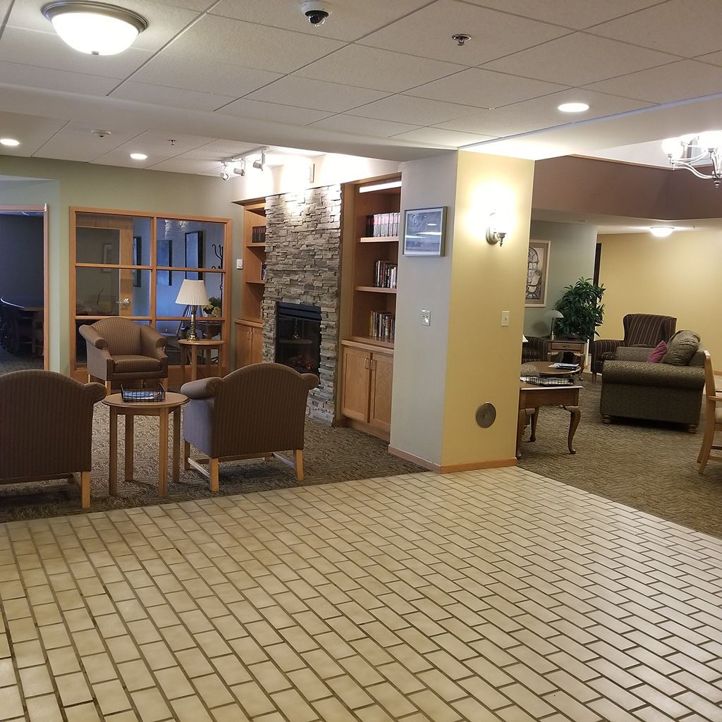 A spacious lobby with comfortable chairs, a stone fireplace, and built-in wooden shelves in a cozy lounge area.