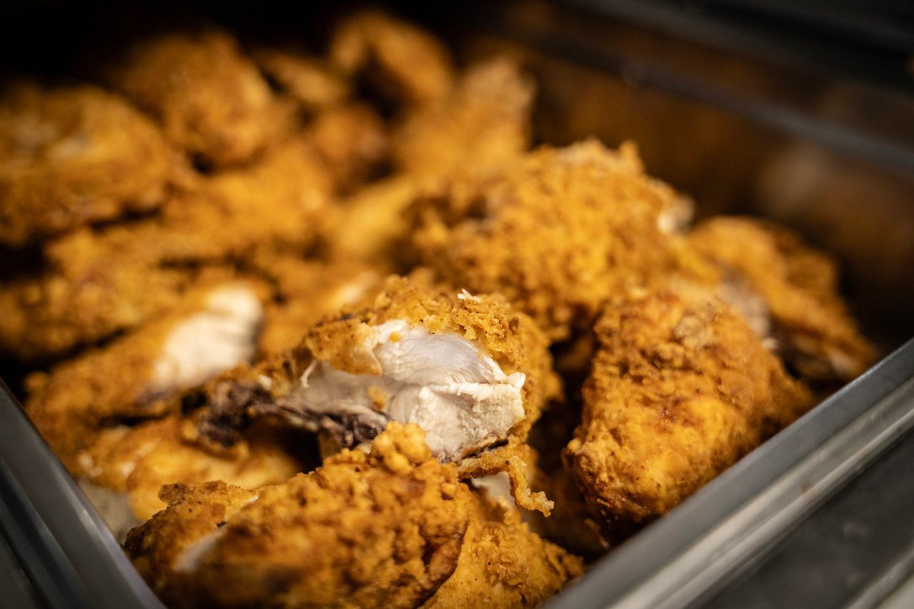 A metal tray filled with golden-brown, crispy fried chicken pieces.