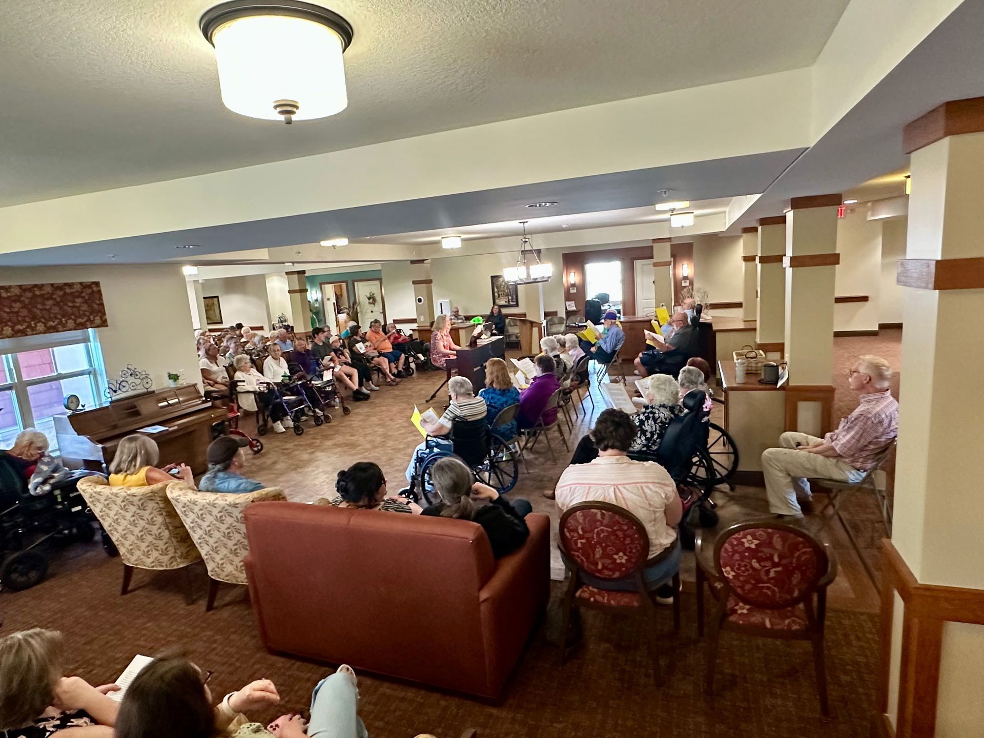 A group of people seated in a common area for a presentation or gathering in a residential or community facility.