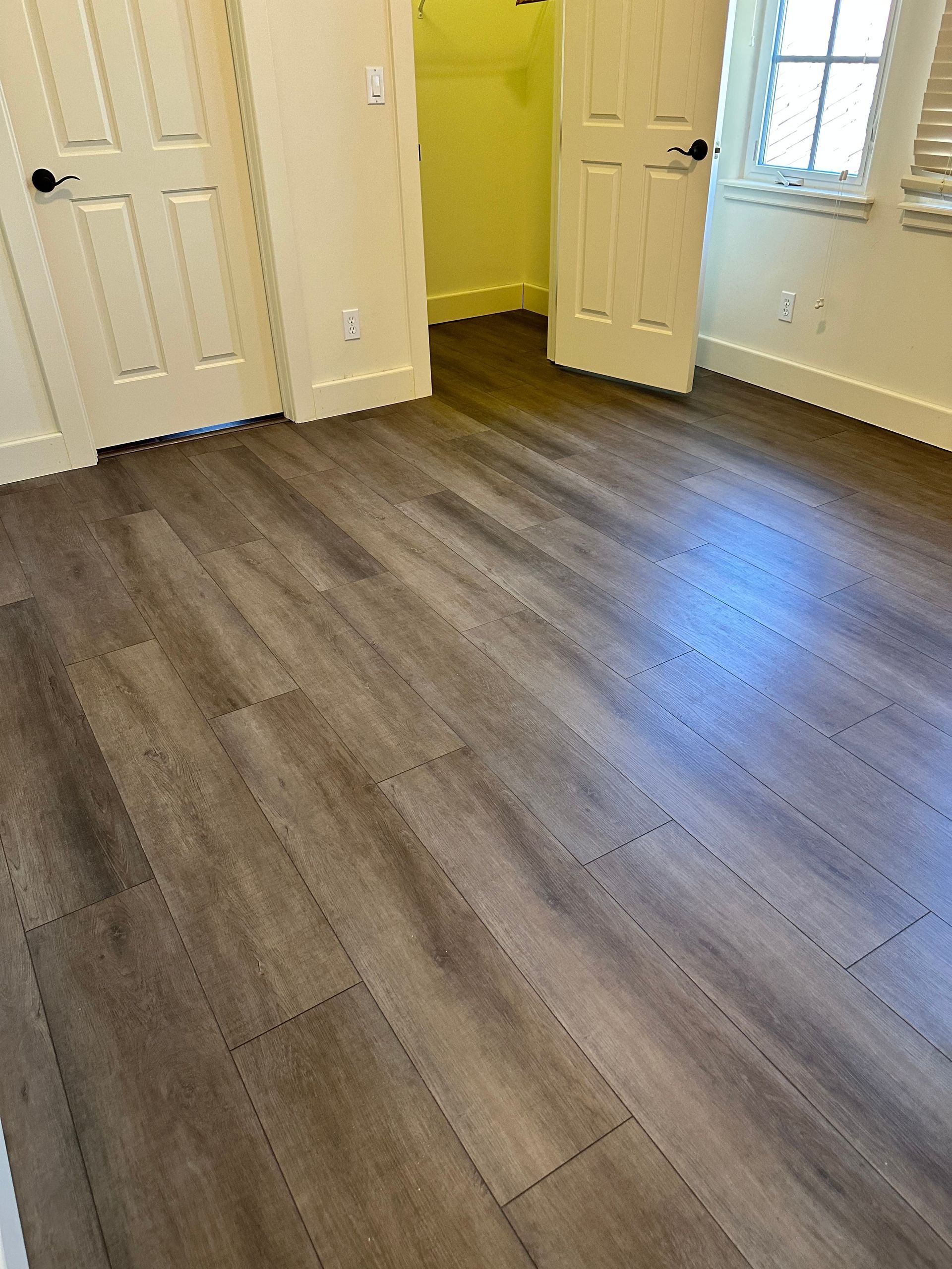 A bedroom with hardwood floors and white doors.