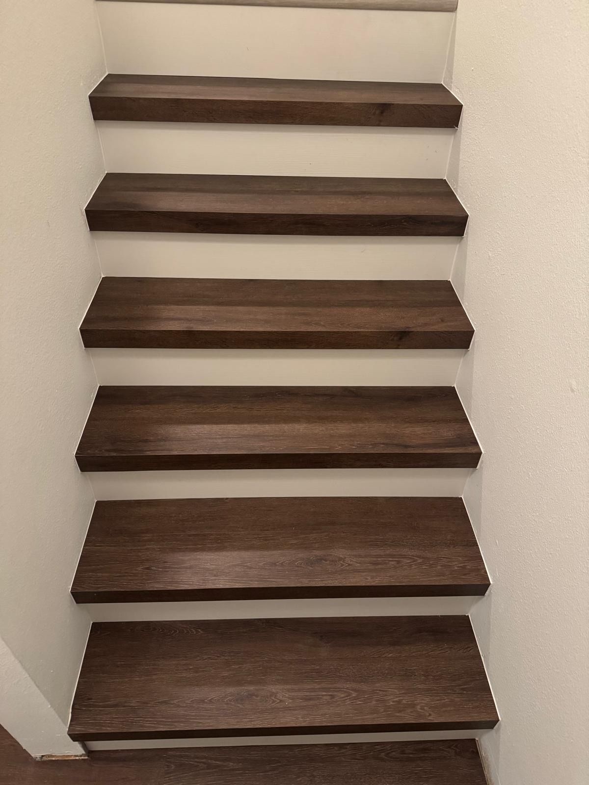 A set of wooden stairs leading up to a white wall.