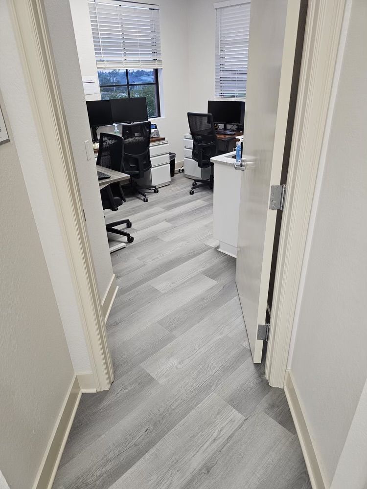 A hallway leading to a small office with two desks and chairs.