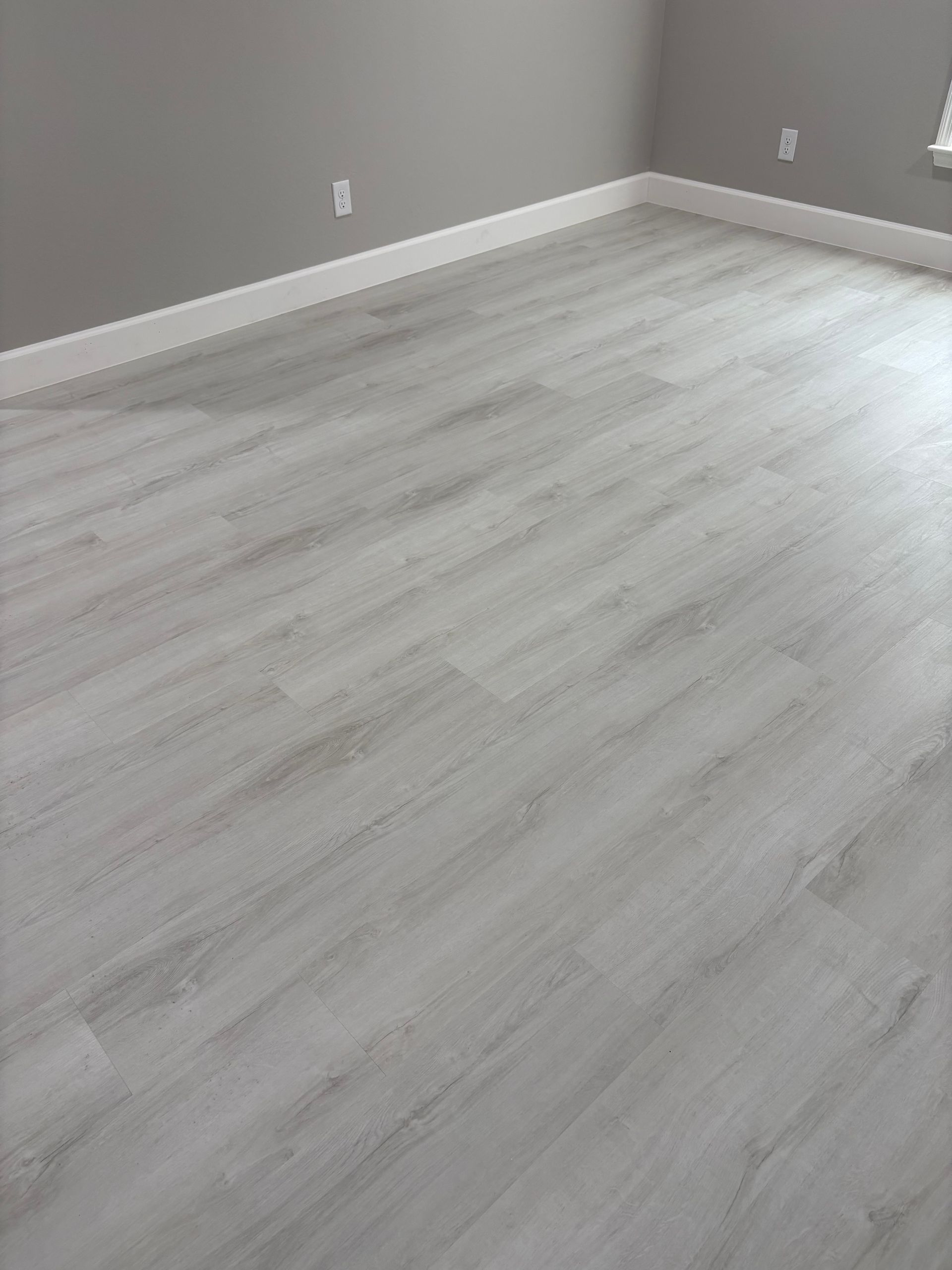A room with a white wooden floor and gray walls.