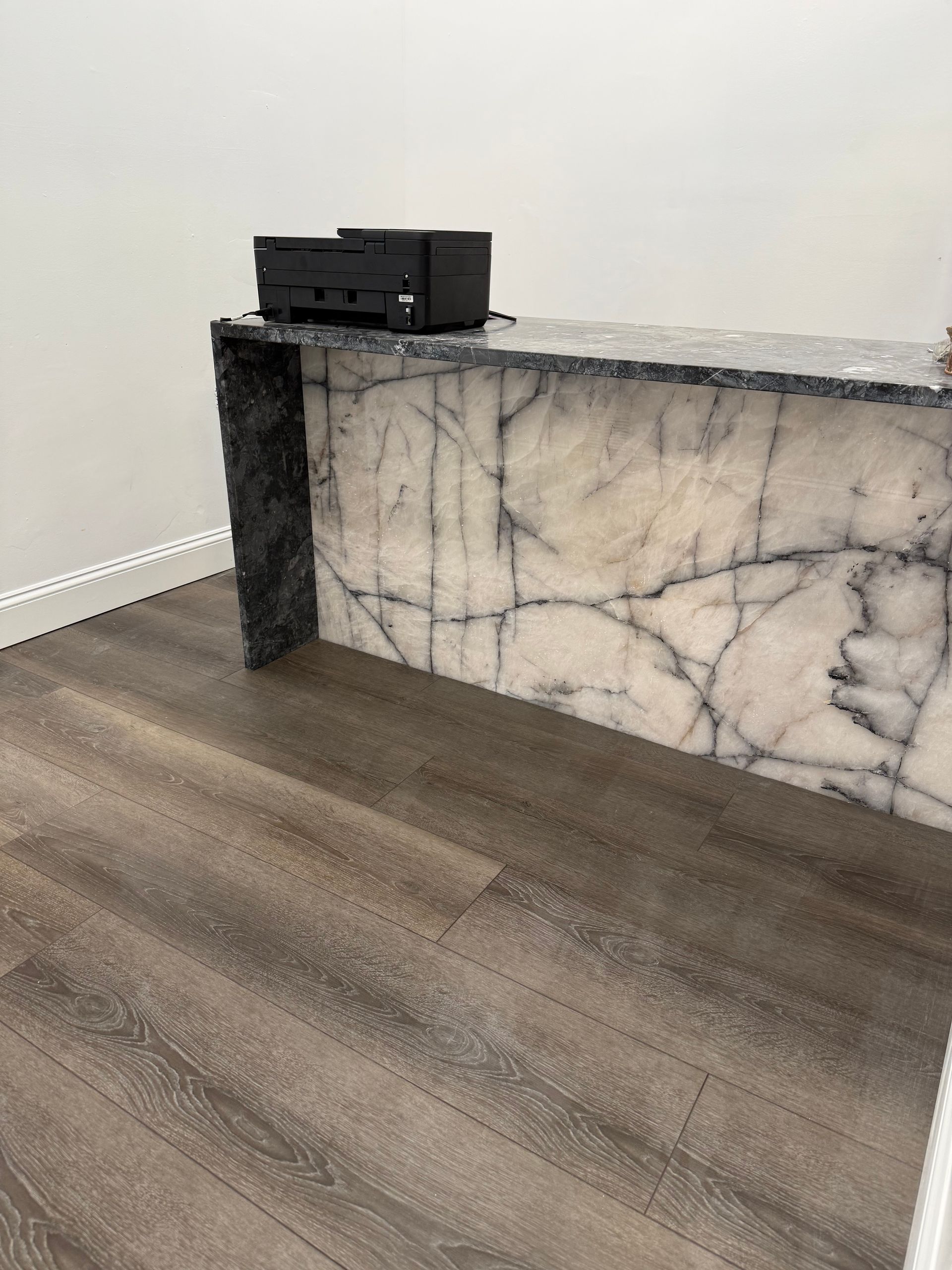 A marble counter top with a printer on top of it in a room.