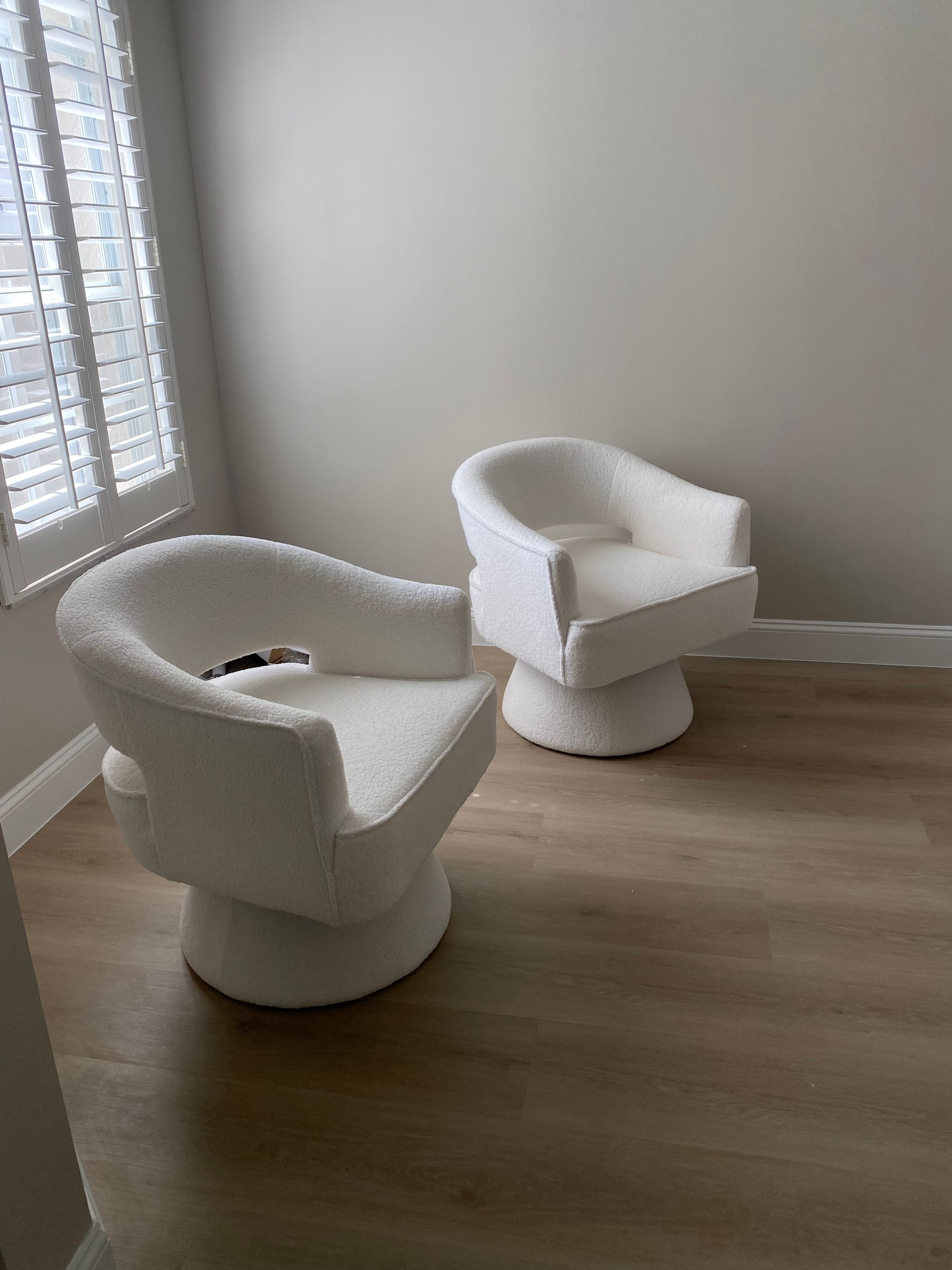Two white chairs are sitting next to each other in a room.