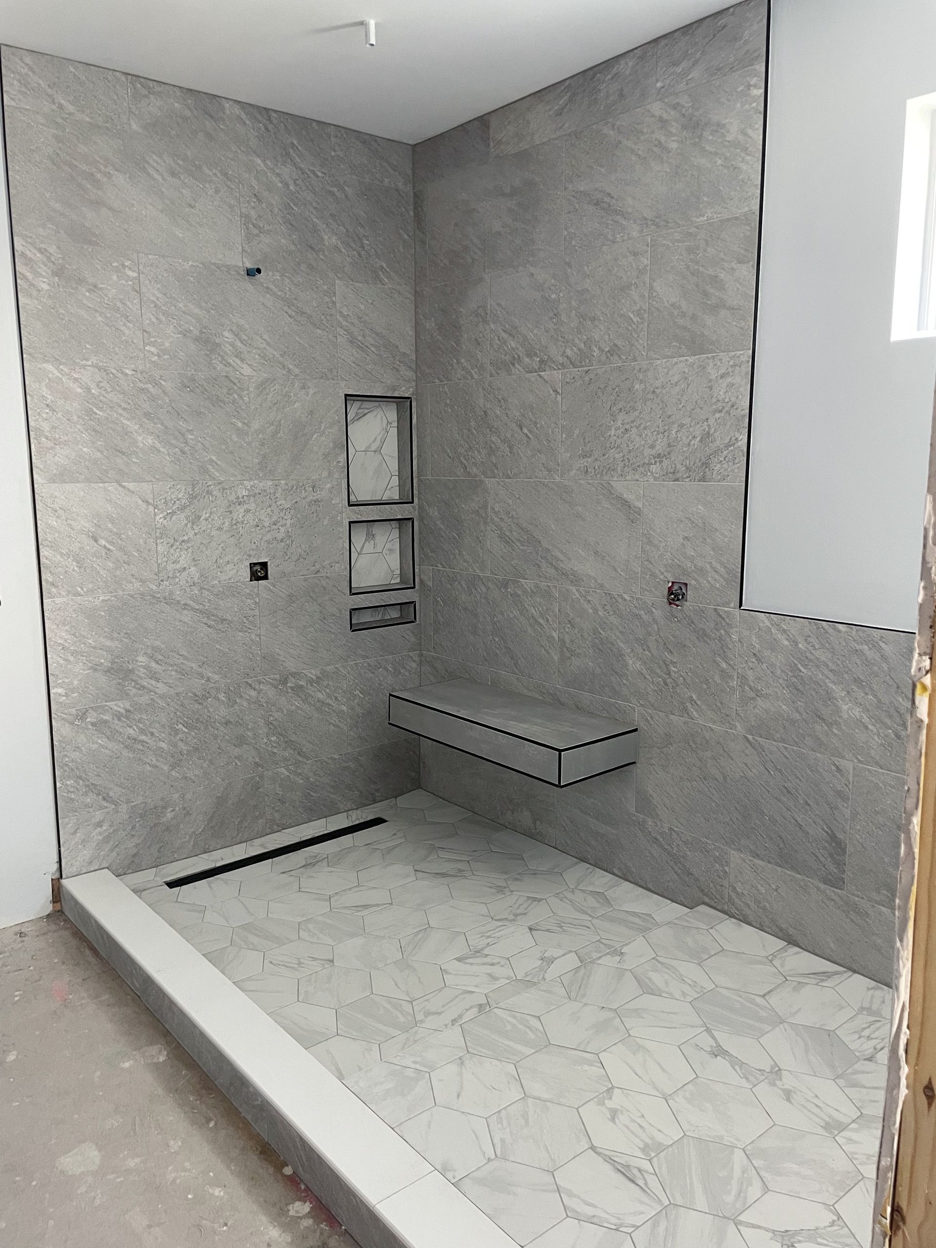 A bathroom with a walk in shower and a bench.