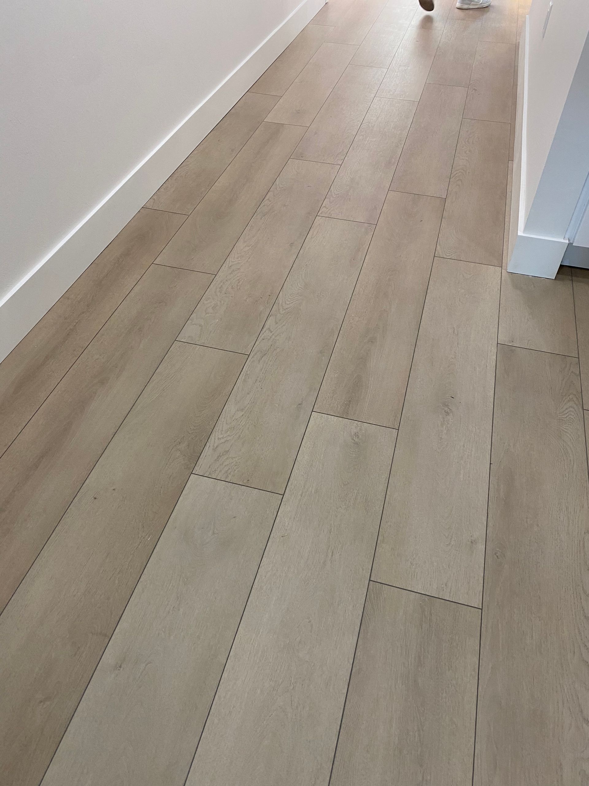 A person is standing on a wooden floor in a hallway.