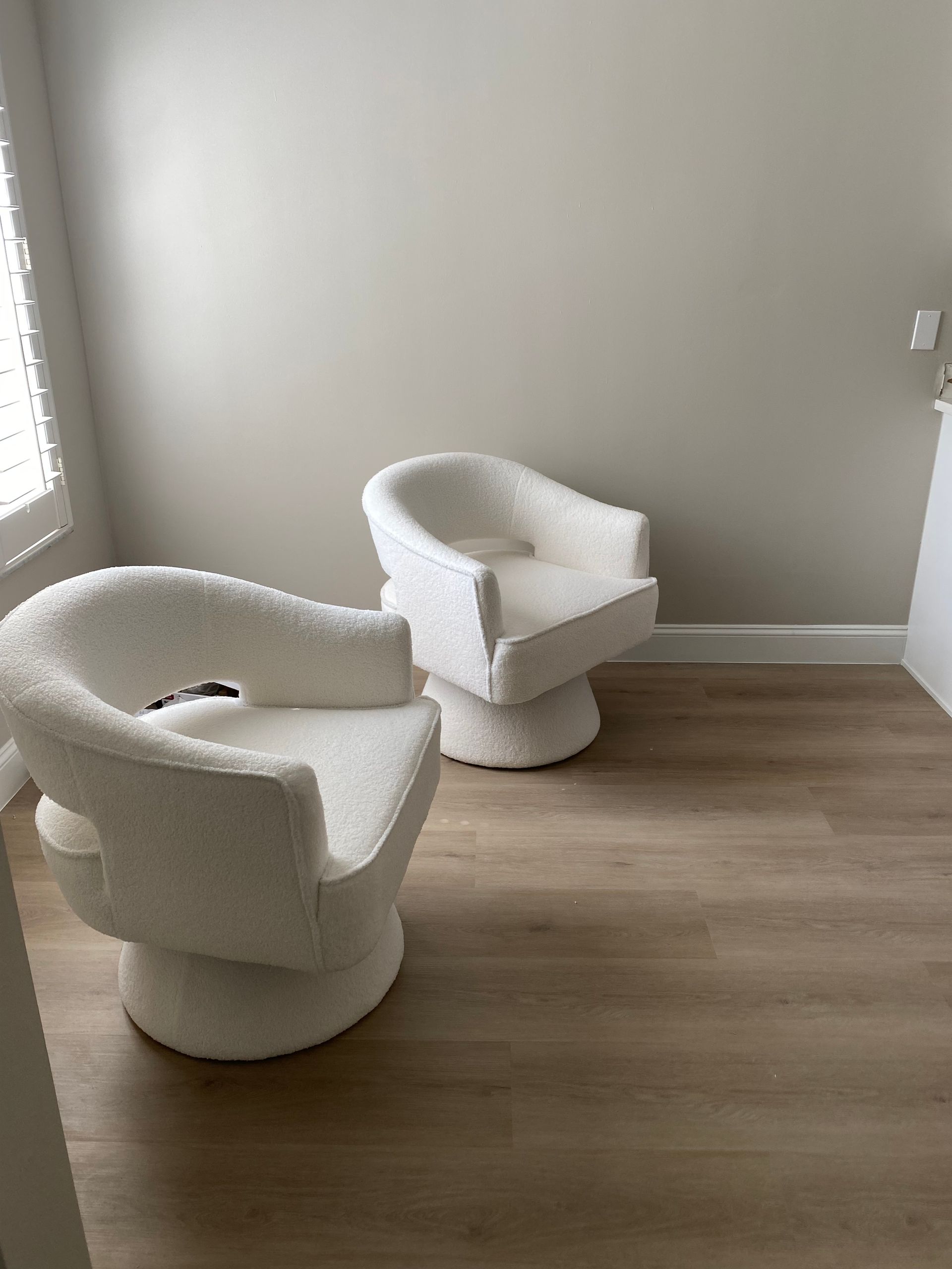 Tan SPC flooring by Style Home Remodeling installed in a Fort Myers home, featuring two modern chairs resting on the wide vinyl planks.