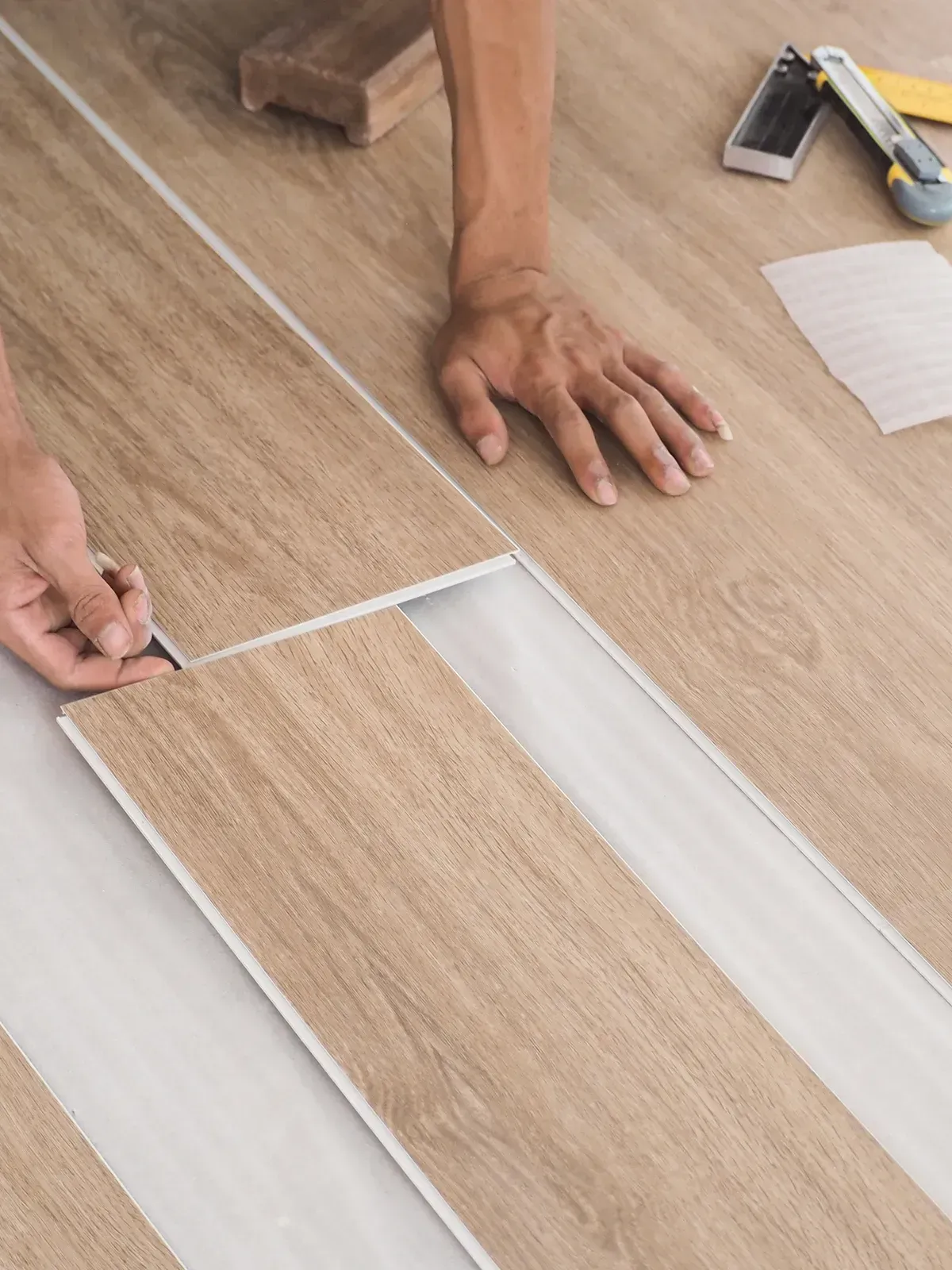 A person is installing a wooden floor in a room.