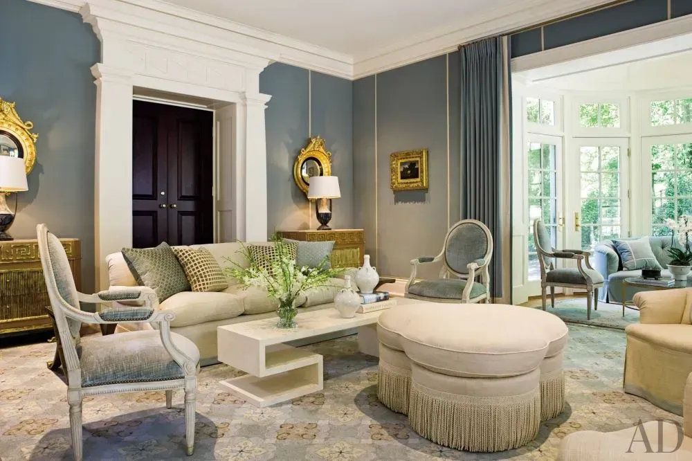 A living room with a couch , chairs , ottoman and coffee table