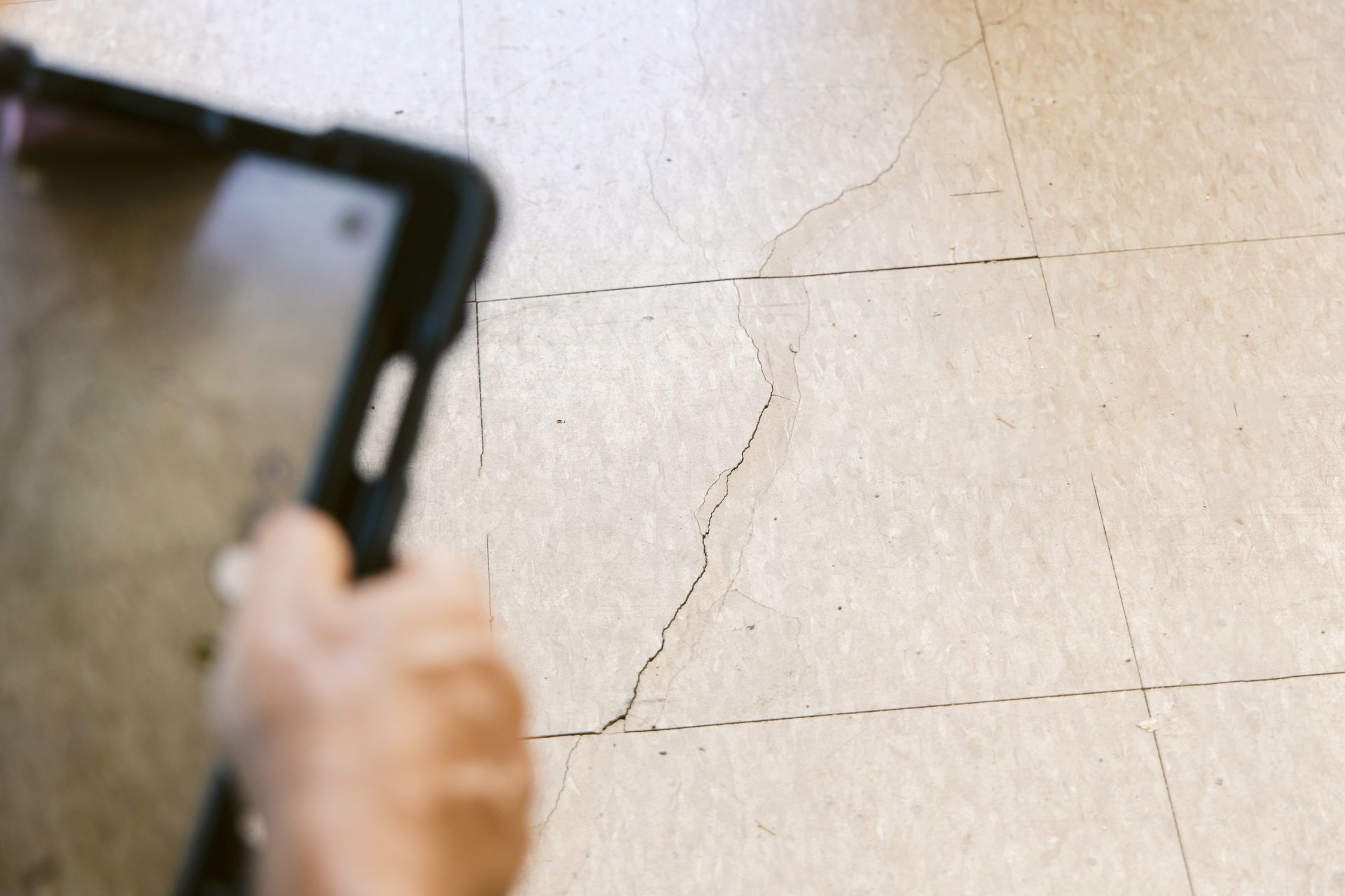 Specialist documenting a cracked concrete floor during a Houston foundation repair inspection