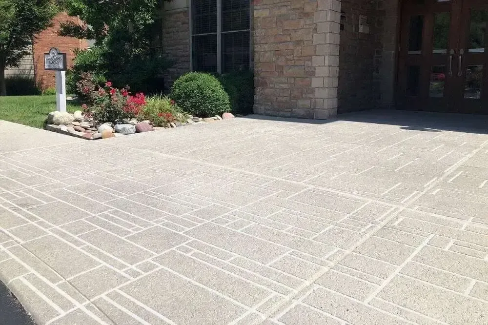 Textured concrete walkway with geometric white lines leading to a building entrance.